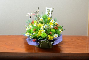 一番人気の「宝づくし」（10,800円）。白梅、日本水仙、小菊、ピンポンマム、千両、小松など。新春にふさわしい和の花々をふんだんに使って宝船のような風情で。