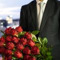 赤バラの花束を持った男性の画像