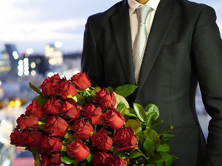 赤バラの花束を持った男性の画像