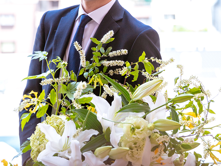 スーツを着た男性とユリの花束