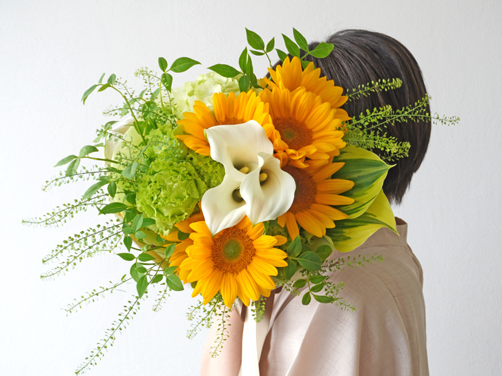 ヒマワリの花束を持つ女性